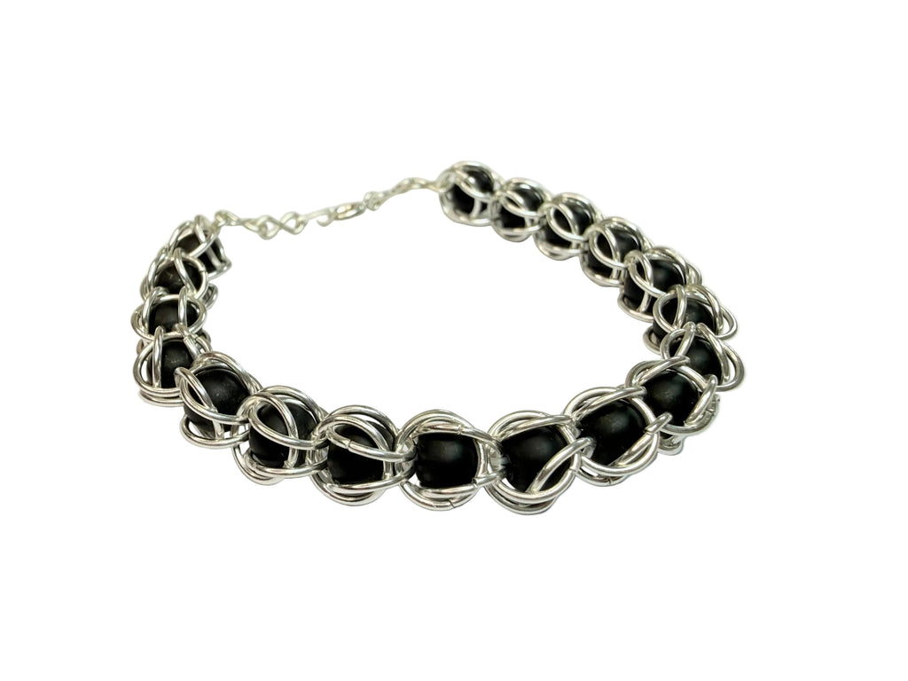 Bracelet with black beads and silver links on a light gray background