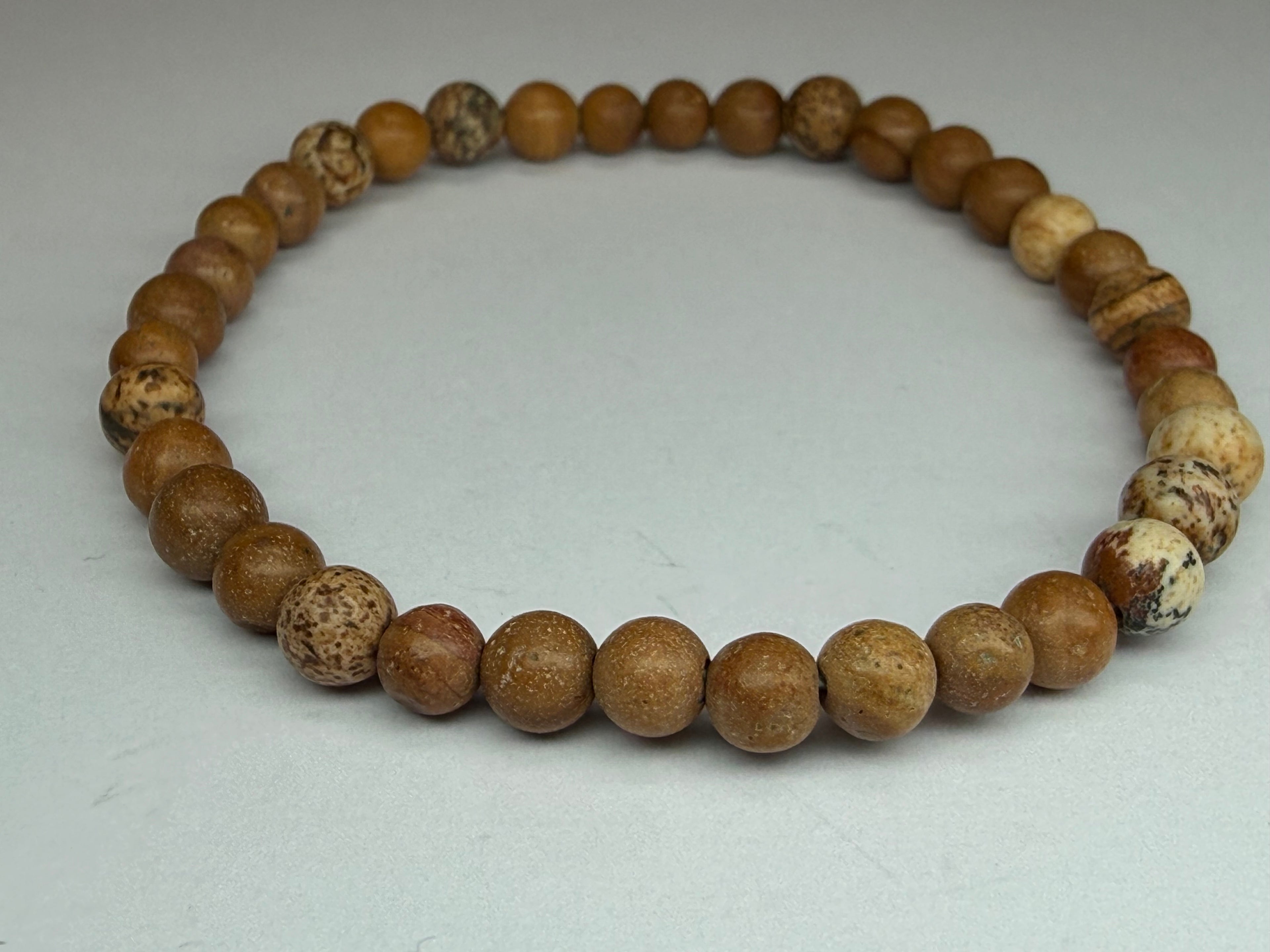 Bracelet made of brown and beige beaded stones on a light gray background