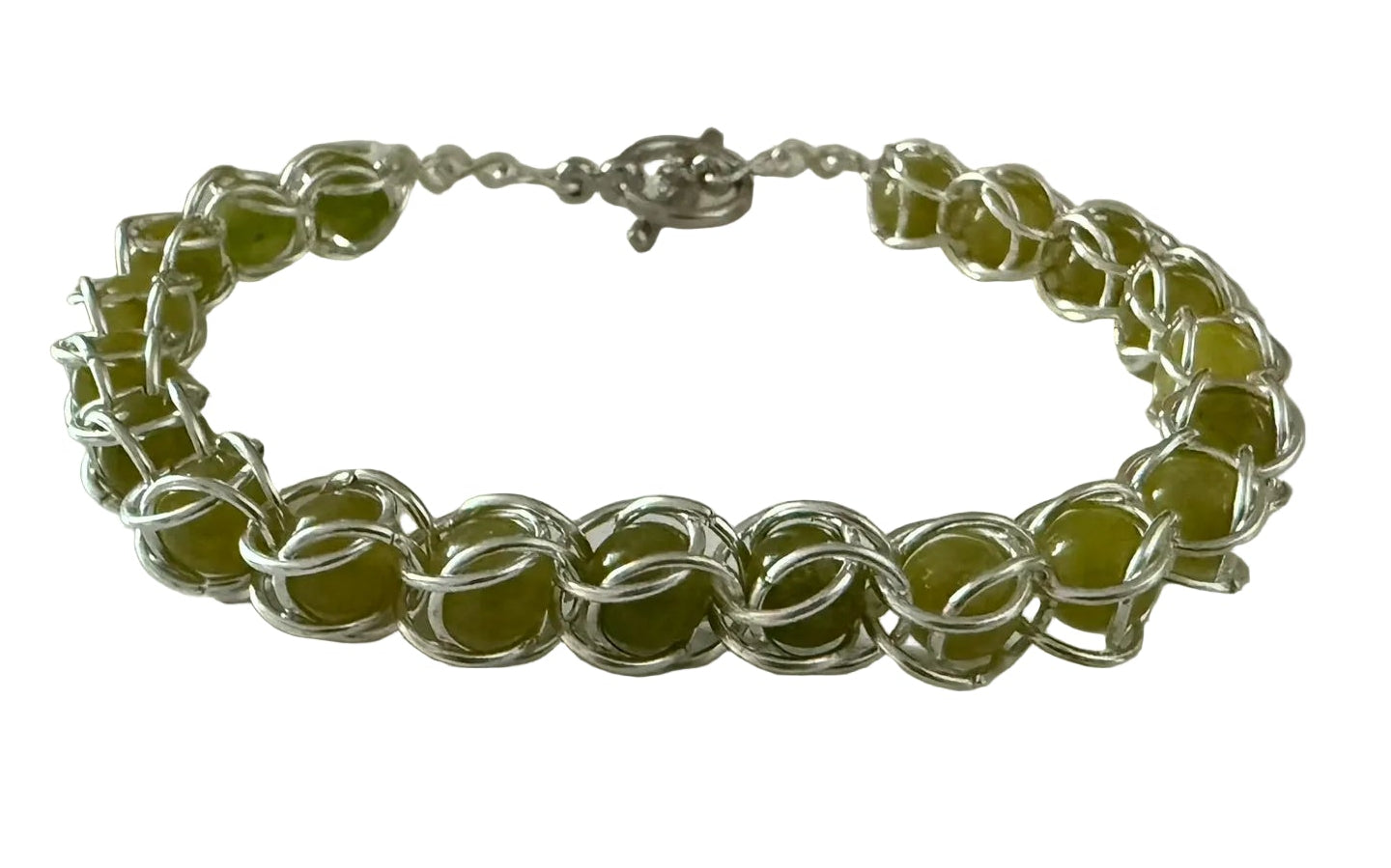 Silver bracelet with green beads on a white surface